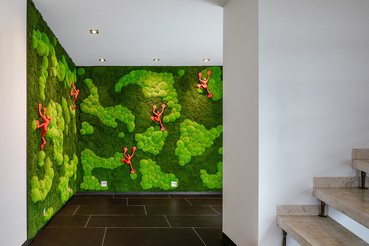 Ballenmoos Mooswandverkleidung mit roten, kletternden Figuren in einem Treppenaufgang