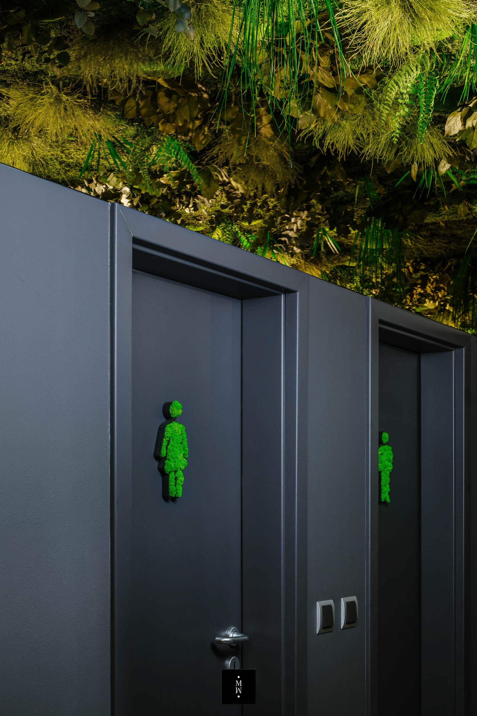 Dschungelmoosdecke in einem Toilettendurchgang mit Moosfiguren für die Toilettentüren