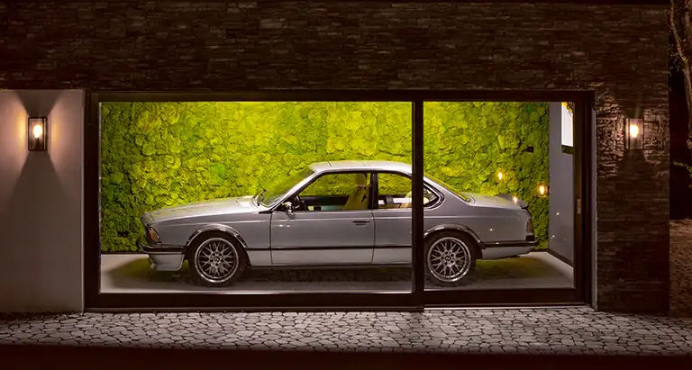 Garage mit Oldtimer vor einer beleuchteten Wand aus Bärenfell von MoosMoos, exklusives nachhaltiges Naturdesign für private Räume